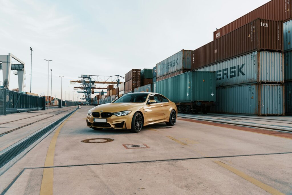 gold BMW next to a shipping container